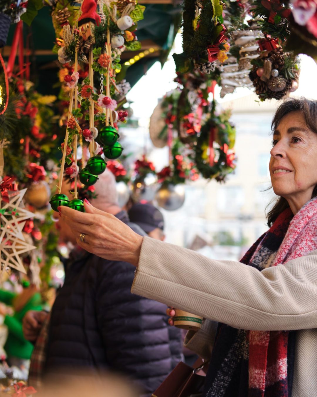Senior woman enjoying christmas shopping, choosing decorations at an outdoor market